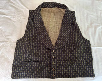 Op de afbeelding: Een mouwloos vest van donkere stof met een herhalend klein geel geometrisch ruitpatroon. Het kledingstuk heeft een brede sjaalkraag, vijf knopen aan de voorzijde en twee zakken onderaan. De binnenvoering is beige en bruin geblokt.