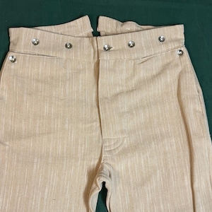 Pantalones de lino con cintura de 34" y botones en la bragueta, con espalda de cola de pez, bolsillos tipo mule para las orejas y el reloj.