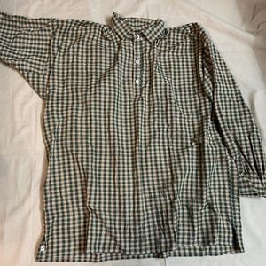 May include: A long-sleeved shirt with a green and beige checkered pattern. The shirt has a button-down collar and a three-button placket. The cuffs are buttoned, and the shirt is made of a lightweight fabric.