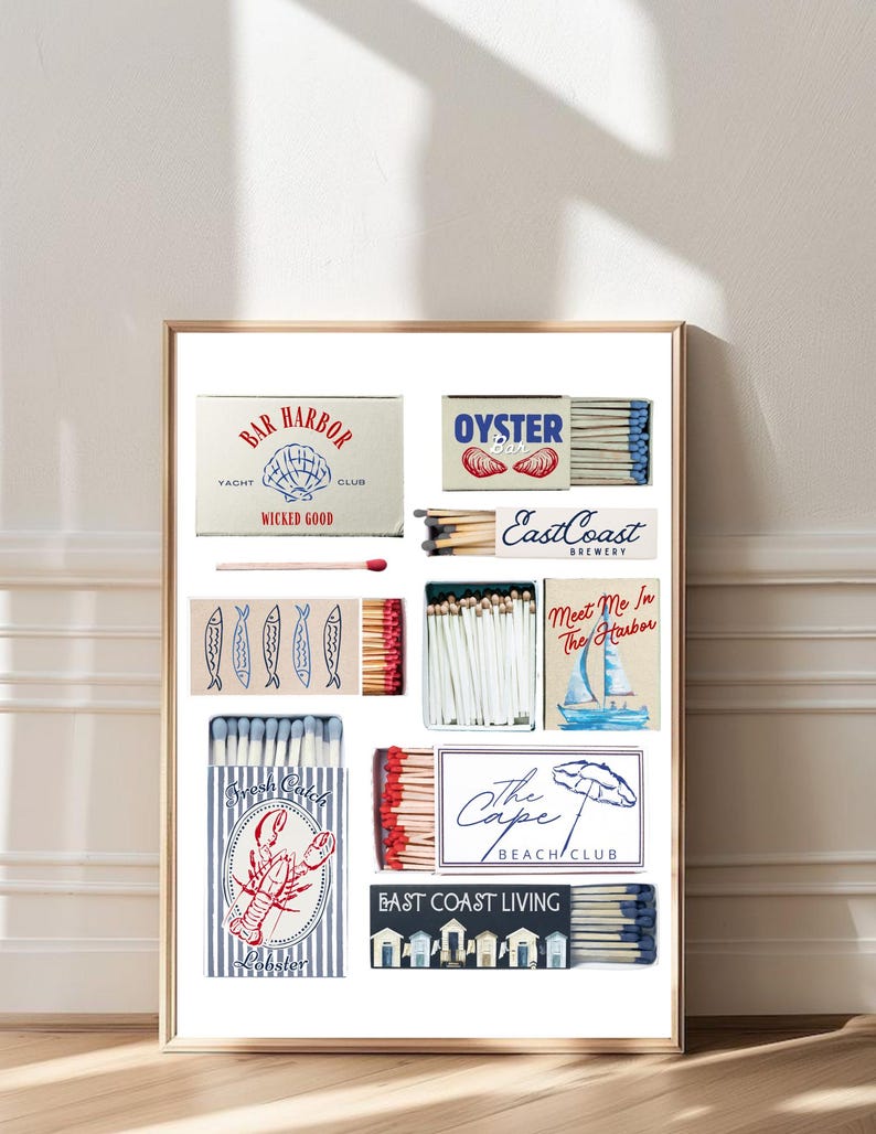 May include: A framed print featuring various matchbox designs with coastal themes. Designs include "Bar Harbor Yacht Club," "Oyster Bar," "East Coast Brewery," and "The Cape Beach Club." The color palette includes red, blue, and white.