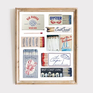 以下が含まれることがあります： 海岸をテーマにしたマッチ箱のデザインが施された額入りのプリント。 「Bar Harbor Yacht Club」、「Oyster Bar」、「East Coast Brewery」などのテキストが表示されています。 他の箱には、魚、ロブスター、ヨットの画像が表示されています。