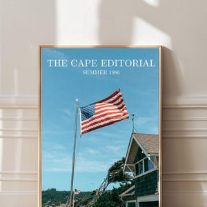May include: A framed print featuring an American flag waving in the wind against a blue sky. The print includes the text "THE CAPE EDITORIAL SUMMER 1986" and a coastal house.