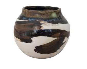 Peut inclure: Un vase en céramique avec un corps arrondi et une large ouverture. Le vase présente une base blanche avec des coups de pinceau bruns et noirs. Le bord est brun foncé. Ce vase décoratif convient à la décoration intérieure.