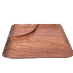 Könnte beinhalten: Ein quadratisches Serviertablett aus Holz mit einem gebogenen Abschnitt. Das Tablett ist aus hellbraunem Holz gefertigt und hat eine glatte, polierte Oberfläche. Das Tablett ist zum Servieren von Snacks oder Vorspeisen konzipiert.