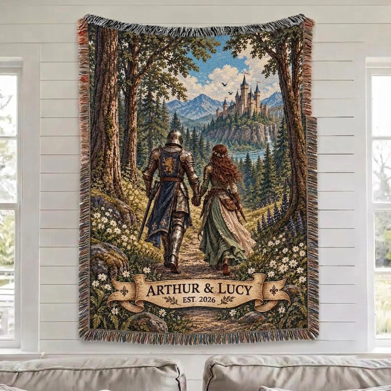 Pu&ograve; includere: Una coperta in arazzo intrecciato raffigurante un cavaliere in armatura e una persona con un abito lungo che camminano attraverso una foresta verso un castello. La scena include montagne, alberi e fiori. Un banner mostra ARTHUR & LUCY EST. 2026.