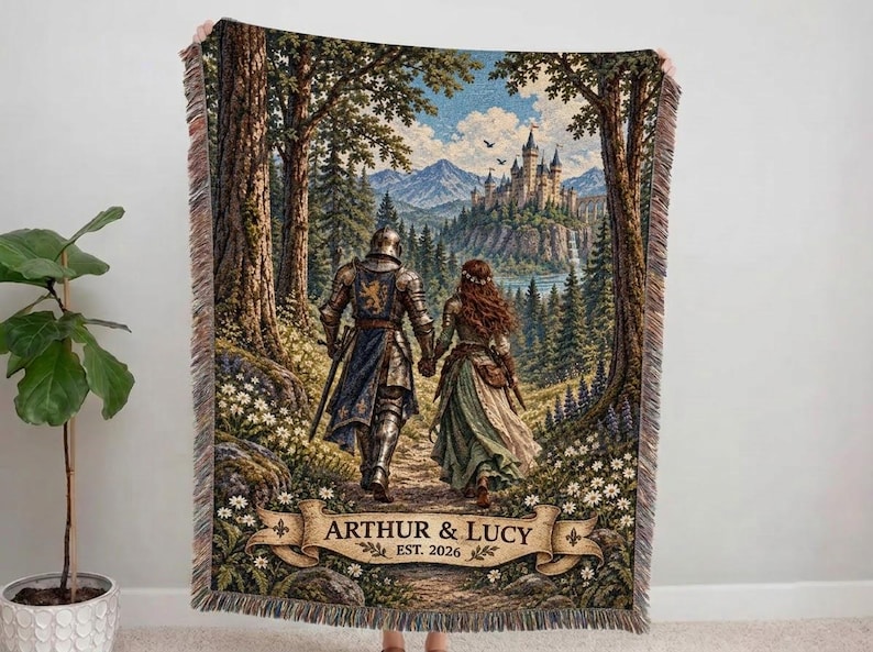 Pu&ograve; includere: Una coperta tessuta che raffigura un cavaliere in armatura e una persona con un abito lungo che camminano attraverso una foresta verso un castello. La scena include uno stendardo in basso con il testo ARTHUR & LUCY EST. 2026 e frange decorative.