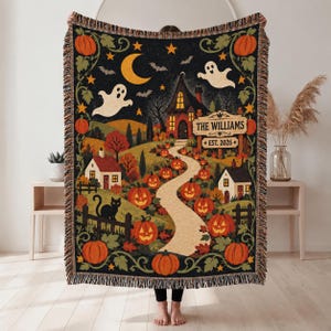 May include: A woven throw blanket featuring a Halloween scene with a haunted house, a winding path lined with orange pumpkins, two small houses, a black cat, ghosts, bats, and a crescent moon. The text reads THE WILLIAMS EST. 2026.