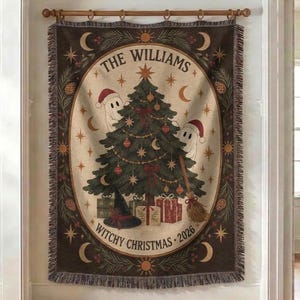 May include: A rectangular woven tapestry hanging on a wooden rod, featuring a dark brown border with pine branches and moons. The centre shows a Christmas tree, two ghosts in Santa hats, gifts, a witch hat, and text reading THE WILLIAMS WITCHY CHRISTMAS 2026.