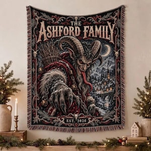 Pode incluir: Uma manta de tapeçaria tecida apresentando uma criatura escura com chifres, língua comprida, olhos vermelhos e pelo, contra uma paisagem de aldeia nevada. O texto diz THE ASHFORD FAMILY no topo e EST. 2026 na base, com bordas ornamentadas.