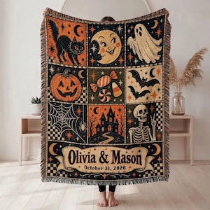 Puede incluir: Una manta tejida con una cuadrícula de ilustraciones de Halloween que incluyen un gato negro, luna creciente, fantasma, calabaza, dulces, murciélagos, telaraña, casa embrujada y esqueleto. El texto dice Olivia & Mason October 31, 2026.