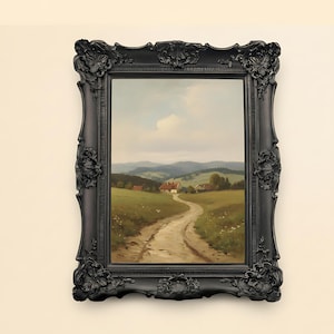 May include: A framed landscape painting featuring a winding dirt road leading to a small village nestled in a valley. The painting is set in a black ornate frame. The artwork depicts a serene countryside scene with rolling hills and a cloudy sky.