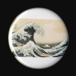 May include: A white button with a colorful image of a large wave crashing against a mountain. The wave is blue, green, and white, and the mountain is brown and white.