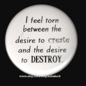 May include: A white button with black text that reads "I feel torn between the desire to create and the desire to DESTROY." The text is centered on the button. The button is round and has a white background.
