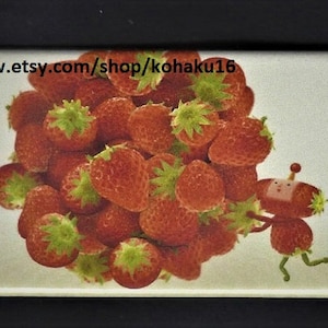 May include: A close-up image of a pile of red strawberries. The strawberries are arranged in a heap, with some of them spilling over the edges. There is a small cartoon character in the lower right corner of the image.