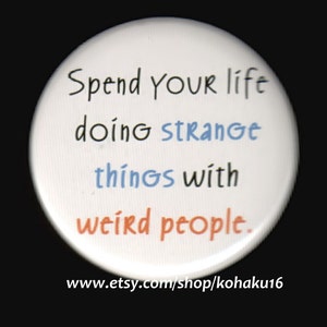 May include: White button with black text that reads "Spend your life doing strange things with weird people." The text "weird people" is in orange. The bottom of the button has the website address www.etsy.com/shop/kohaku16.