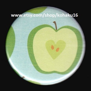 May include: A green apple with a heart-shaped core on a light blue background. The apple has a green outline and a light green center. The heart-shaped core is a light green color with two orange seeds.