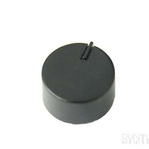 May include: A black, cylindrical control knob with a vertical groove on top. The knob is made of a matte material and is set against a white background. It is likely a component for electronic equipment.
