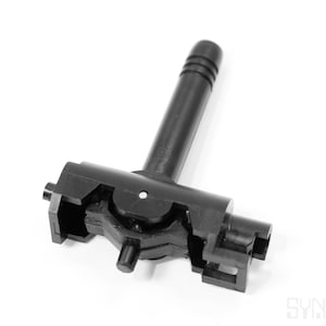 May include: A black plastic component with a T-shaped design. It features a cylindrical handle with ridges and a complex base with various protrusions and openings. The object is set against a white background.