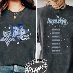 Könnte beinhalten: Dunkelgraues T-Shirt mit blauem Stern-Design, den Worten "Silent Treatment" und "Freya Skye". Auf der Rückseite sind Tourdaten der "Stars Align Tour" abgebildet. Das T-Shirt ist mit "Comfort Color Pepper" gekennzeichnet.