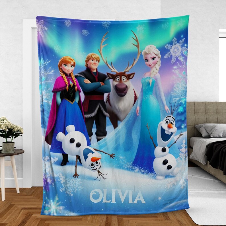 Puede incluir: Una manta azul de forro polar con personajes de la pel&iacute;cula de animaci&oacute;n Frozen. La manta muestra a Anna, Elsa, Kristoff, Sven y Olaf sobre un fondo de copos de nieve y una aurora boreal. El nombre "OLIVIA" est&aacute; impreso en la parte inferior.