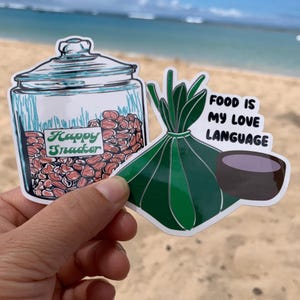 May include: Two stickers featuring food-themed illustrations. The first sticker shows a glass jar filled with red beans with the text "Happy Snacker" on the label. The second sticker shows a green bundle of leaves with a bowl of purple liquid and the text "Food is my love language".