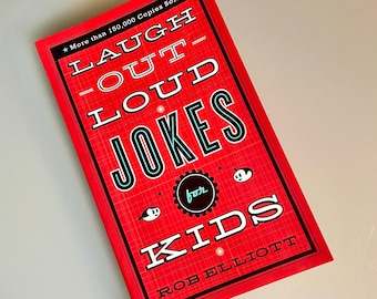 May include: A red book with the title "Laugh Out Loud Jokes for Kids" in black and teal lettering. The book cover has a black and white illustration of a cartoon character with a star and a circle with the word "for" inside. The author's name, "Rob Elliott", is printed in black at the bottom of the cover.