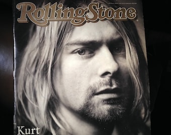 May include: A black and white photo of Kurt Cobain on the cover of Rolling Stone magazine. The magazine cover features the Rolling Stone logo in gold lettering and the text "Kurt Cobain 1967-1994".