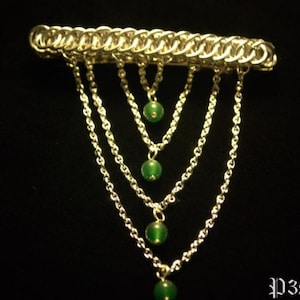 Puede incluir: Un peine para el cabello de malla de cadena plateada con cinco hebras de cadena que cuelgan. Cada hebra tiene una cuenta de piedra preciosa verde al final.