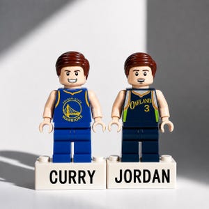 May include: Two Lego figures of basketball players, one in a blue and gold Golden State Warriors jersey and the other in a navy and green Oakland jersey. The figures stand on white blocks labeled "CURRY" and "JORDAN".