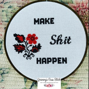 K&ouml;nnte beinhalten: Kreuzstich-Stickerei in einem Holzreifen. Das Design zeigt die Worte "MAKE Shit HAPPEN" in schwarzen Blockbuchstaben, mit einem roten und schwarzen Blumenmotiv. Der Text "Grammy's Cuss Stitch" befindet sich unten.
