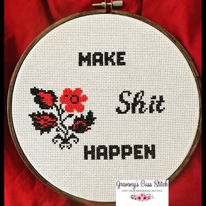 K&ouml;nnte beinhalten: Kreuzstich-Stickerei in einem Holzreifen mit den Worten "MAKE SHIT HAPPEN" in schwarzen Blockbuchstaben. Ein Blumendesign mit roten und schwarzen Akzenten befindet sich auf der linken Seite. Der Hintergrund ist wei&szlig;, vor rotem Hintergrund.