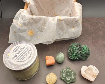 May include: A wooden basket lined with white tissue paper printed with gold celestial designs. The basket contains a candle labeled "Aligned Flame" and various crystals in shades of green, orange, and white.
