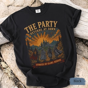 May include: Black t-shirt with a fantasy-themed graphic. The design features the text "THE PARTY RETURNS AT DAWN" above a sunset scene with a castle and figures. Below, it reads "STORIES OF GLORY REMAIN".