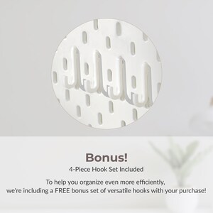 May include: White, circular pegboard with several white hooks. The pegboard has evenly spaced holes for hook placement. Text at the bottom reads "Bonus! 4-Piece Hook Set Included".