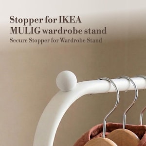 Puede incluir: Tope blanco para un perchero IKEA MULIG. La imagen muestra un primer plano de la parte superior curva del perchero con un tope redondo y texturizado. El texto de la imagen dice "Stopper for IKEA MULIG wardrobe stand" y "Secure Stopper for Wardrobe Stand."