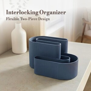 Può includere: Tre organizzatori blu ad incastro con una texture a coste sono esposti su una superficie colorata chiara. Il testo "Interlocking Organizer" e "Flexible Two-Piece Design" sono visibili. Una bottiglia bianca è sullo sfondo.
