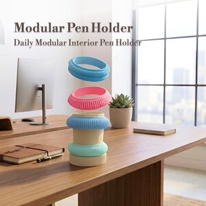 Peut inclure: Un porte-stylo modulaire avec le texte "Modular Pen Holder" et "Daily Modular Interior Pen Holder". Le porte-stylo est composé d'anneaux empilables bleus, roses et verts. Un ordinateur, un cahier et un stylo sont également visibles.