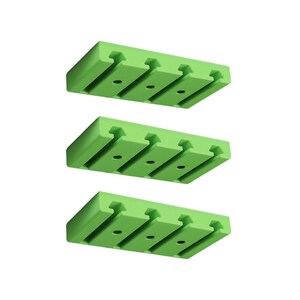 Può includere: Tre organizzatori rettangolari identici in plastica verde lime, ciascuno dotato di tre fessure parallele e tre fori circolari lungo il centro. Questi oggetti sono disposti verticalmente, mostrando un design uniforme con bordi netti e una finitura liscia.