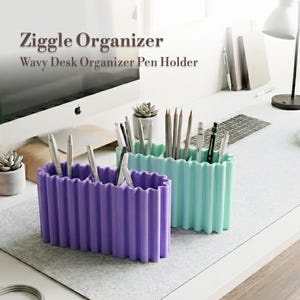 Może przedstawiać: Dwa faliste organizery na biurko, jeden fioletowy i jeden miętowy, oba wypełnione długopisami i ołówkami. Tekst "Ziggle Organizer Wavy Desk Organizer Pen Holder" znajduje się u góry obrazu.