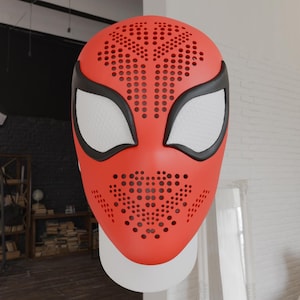 Op de afbeelding: Een rood Spider-Man-masker met zwarte randen en witte ooglenzen. Het masker heeft een geperforeerd patroon over het gezicht en wordt gepresenteerd tegen een witte achtergrond. Een accessoire voor superhelden kostuums.
