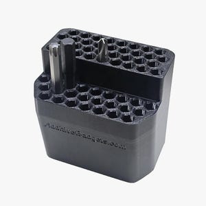 May include: Black 3D-printed tool holder with a honeycomb pattern. The holder has two levels and contains several drill bits and a cylindrical tool. The website address "AdditiveGadgets.com" is printed on the side.