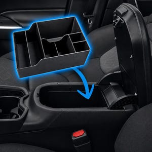 May include: A black plastic car center console organizer tray featuring multiple compartments of varying sizes for storage. The tray is shown hovering above an open vehicle center console storage bin, indicating its placement inside the compartment.