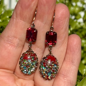 May include: Red and gold dangle earrings with a red square stone and a red oval stone with gold and green glitter.