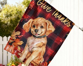 Pode incluir: Bandeira decorativa para exterior com um cachorrinho golden retriever, rodeado por folhas de outono e abóboras. A bandeira tem um fundo xadrez vermelho e preto com a inscrição dourada "Give Thanks".