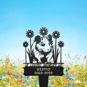 Könnte beinhalten: Schwarzer Metall-Gartenstecker mit einem ausgeschnittenen Design eines Hamsters, umgeben von Blumen. Der Text "IN LOVING MEMORY OF GIZMO 2023-2025" ist auf einem Banner zu sehen. Der Hintergrund ist eine Wiese mit Wildblumen.
