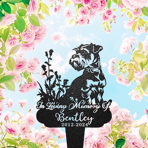 Puede incluir: Estaca conmemorativa de metal negro con la silueta de un perro, con el texto "In Loving Memory Of Bentley 2012-2024". El perro está representado sentado frente a hierba. El fondo es un cielo azul con flores rosas.