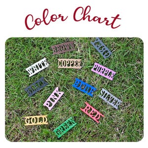 May include: A colour chart with the words "Color Chart" in a cursive font. The chart displays small, rectangular wooden cutouts, each labelled with a different colour name: white, black, brown, copper, blue, pink, red, green, silver, gold, and purple.