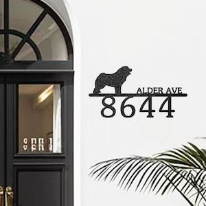 Peut inclure: Panneau d'adresse en métal noir avec une silhouette de chien, le texte "ALDER AVE" et le numéro "8644". Le panneau est monté sur un mur blanc, près d'une porte.
