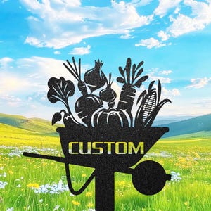 Op de afbeelding: Zwarte metalen tuinpaal met een kruiwagen silhouet gevuld met groenten. De kruiwagen heeft het woord "CUSTOM". De achtergrond toont een bloemenveld, groen gras en een blauwe lucht met wolken.