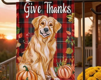 Pode incluir: Bandeira de jardim decorativa com o texto "Give Thanks" e um cão golden retriever. A bandeira tem um fundo xadrez vermelho e preto com abóboras e folhas de outono. O cão está sorrindo.